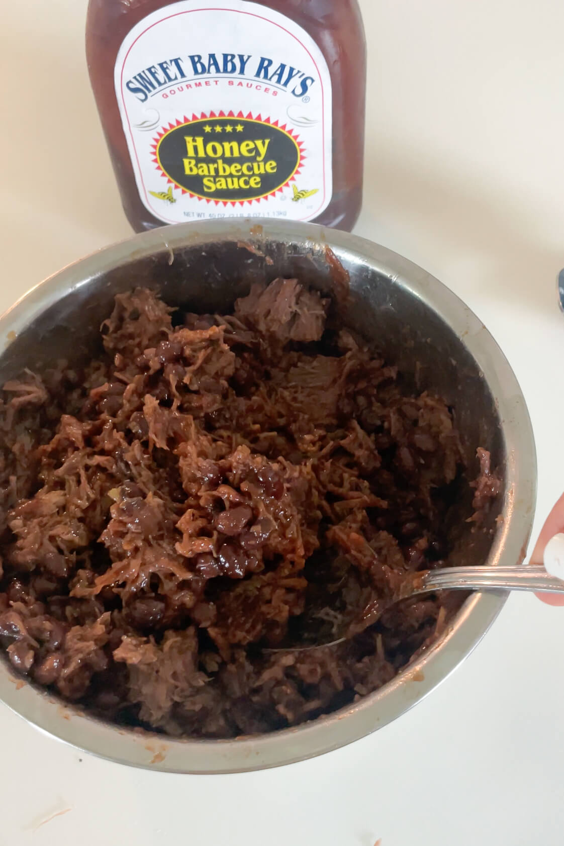 Mixing smoked brisket with BBQ sauce.